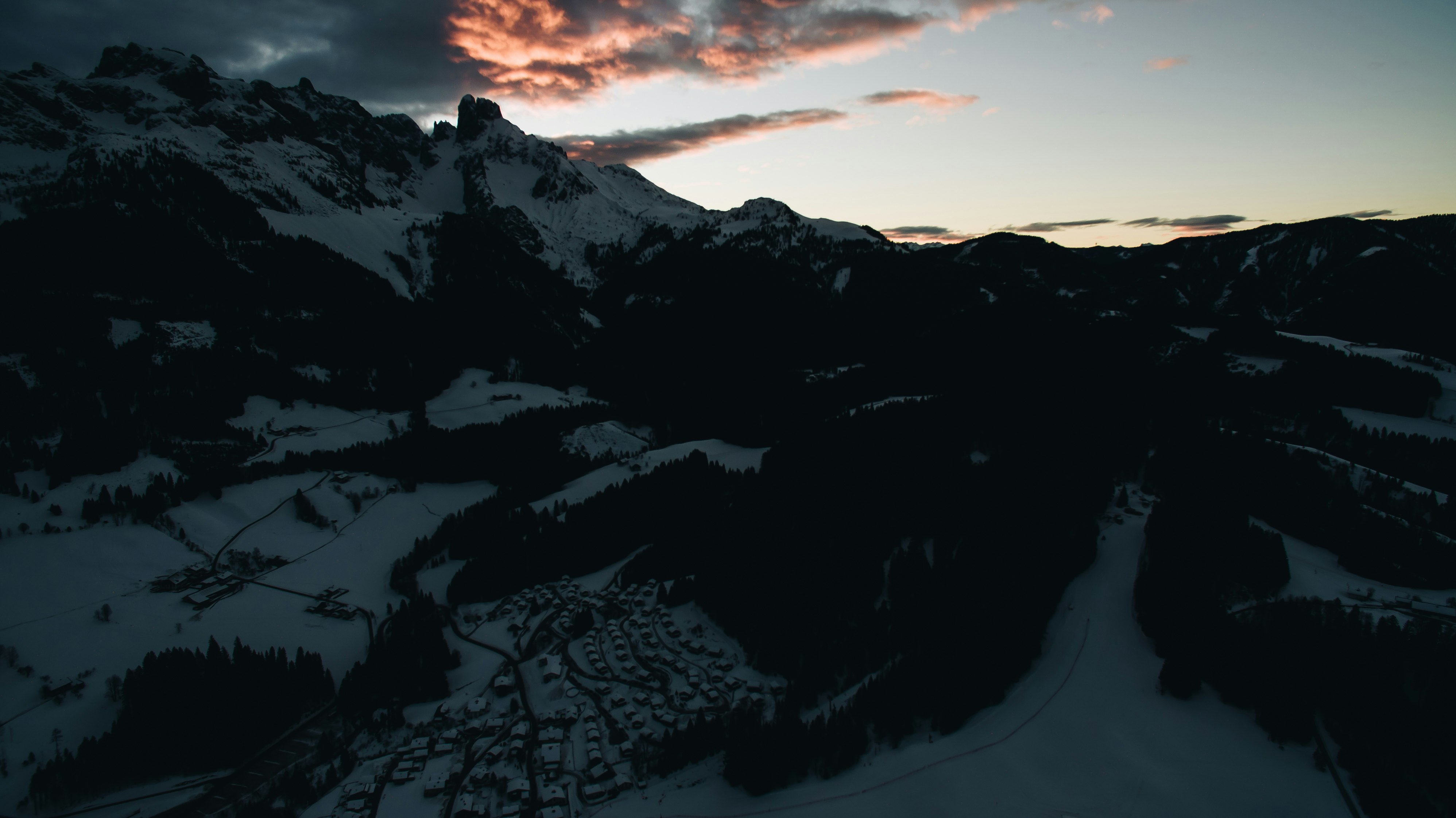 aerial view of snow covered mountain under clouds